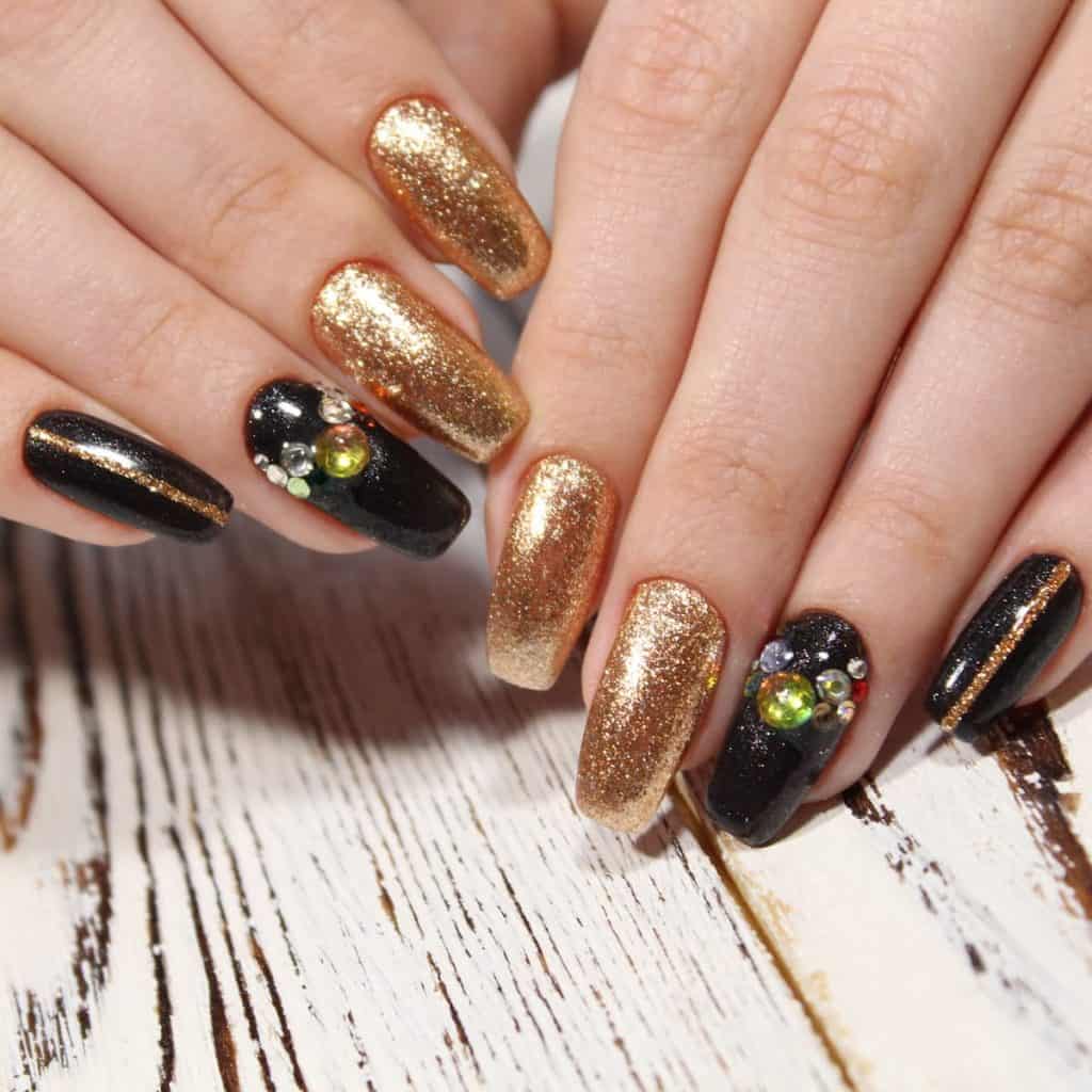 A woman's hands with Gold and black nail designs are made instantly edgy thanks to the combination of two bold hues. 