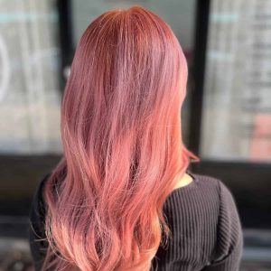 The back of a woman with rose gold hair in front of a store.