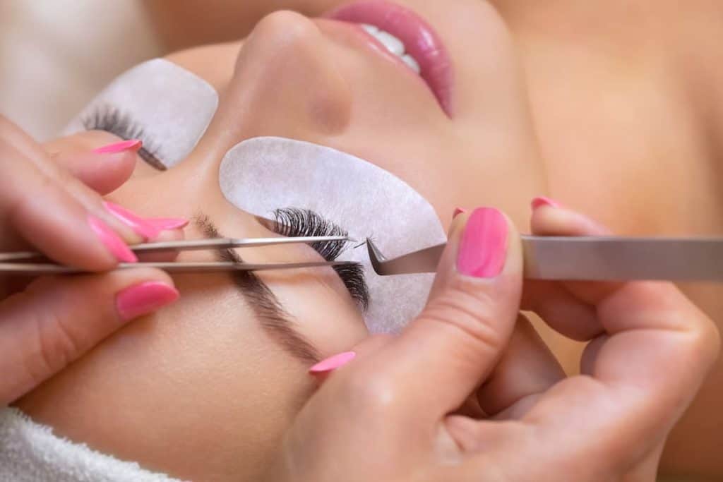 A woman exploring different eyelash extension styles in a beauty salon.