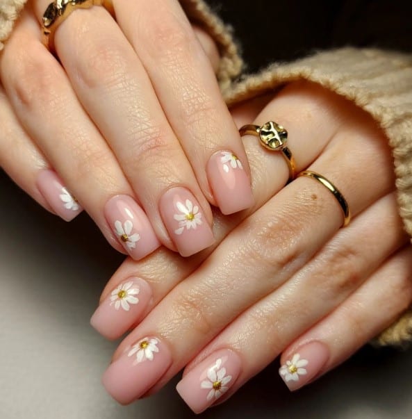 A woman's nude nails with daisies on their nails.