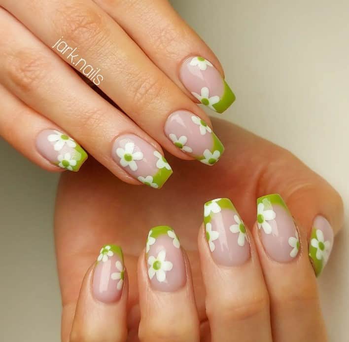 A woman's nails with soothing green French tips and dreamy white flowers