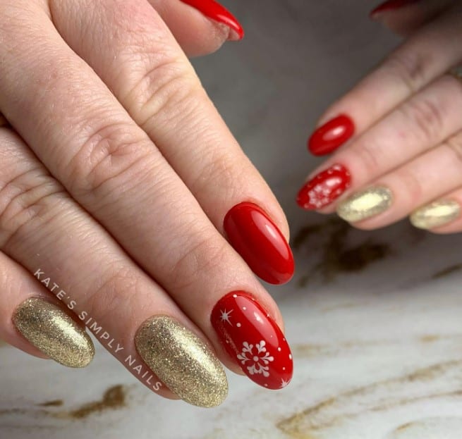 A woman's hands with red and gold nails with christmas designs.