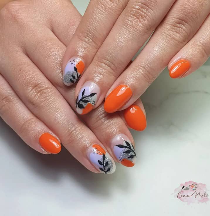 A woman's hand with nails are painted orange, while the accent nails simply have a glossy nude base