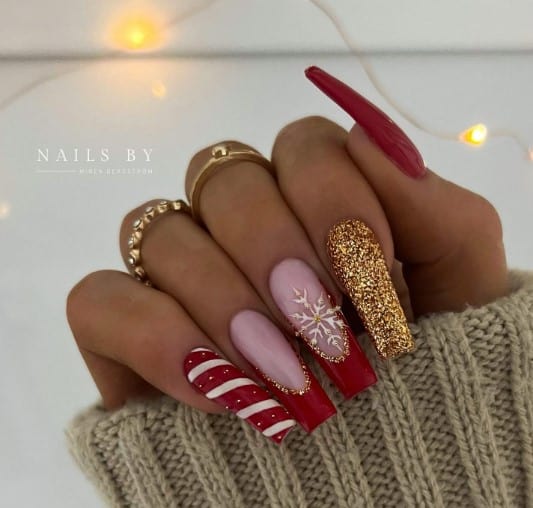 A woman wearing a sweater with christmas-themed red and gold nails.