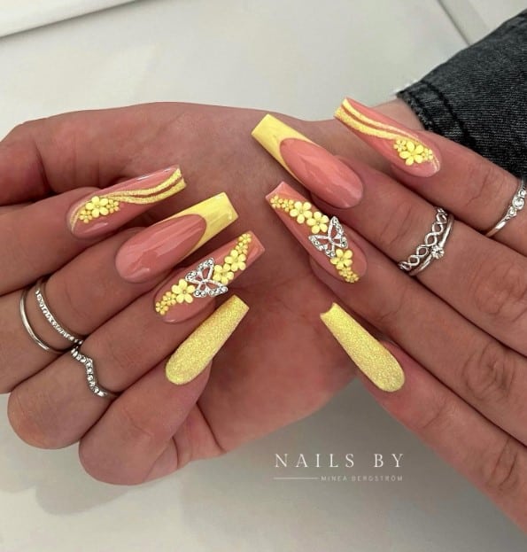A woman's hands with brown and yellow set features a trail of yellow flower stickers with glitter swirls and silver butterflies for accent