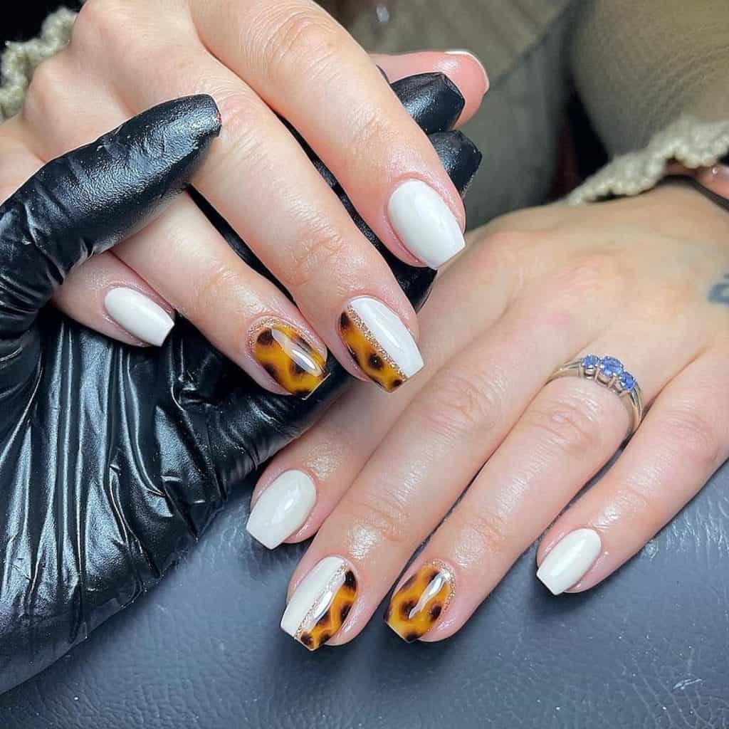 A woman with some nails are pure white; others display an intricate tortoiseshell pattern and a golden reverse French tip