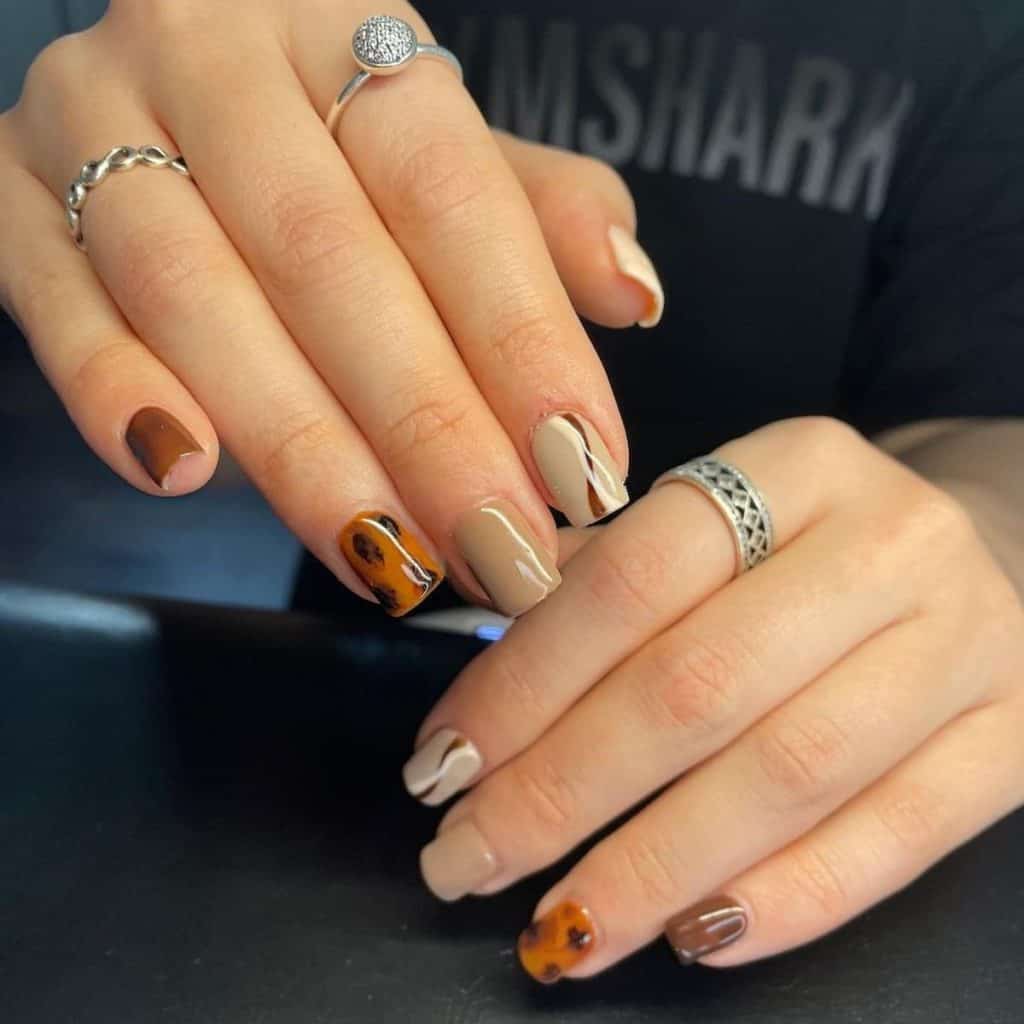 A woman with nail design trend mirrors the varying shades of coffee, transitioning from a deep espresso hue on the pinky to a soft latte shade on the thumb