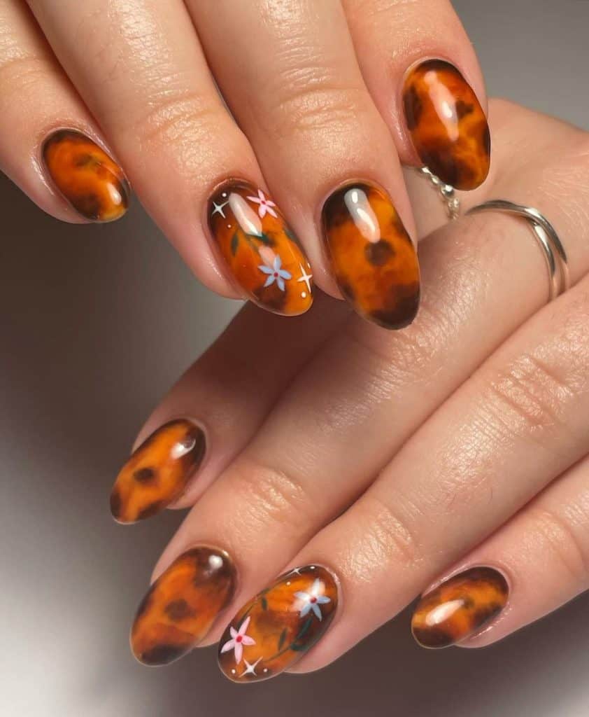 A woman's classic tortoiseshell manicure painting one with dotted white star art and pink and blue floral designs