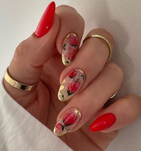 A woman's hand with red nails and accent nails are adorned with roses painted in a watercolor effect, while corners shimmer with flecks of gold foil.