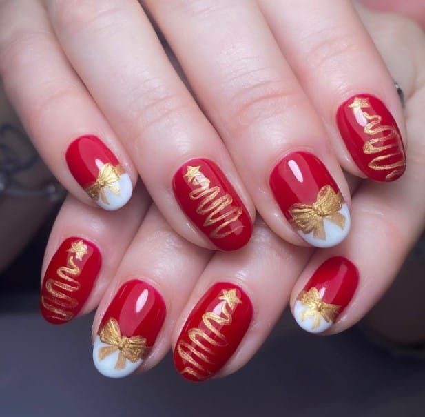 A woman's hand with red nails and has gold ribbon and christmas tree on them