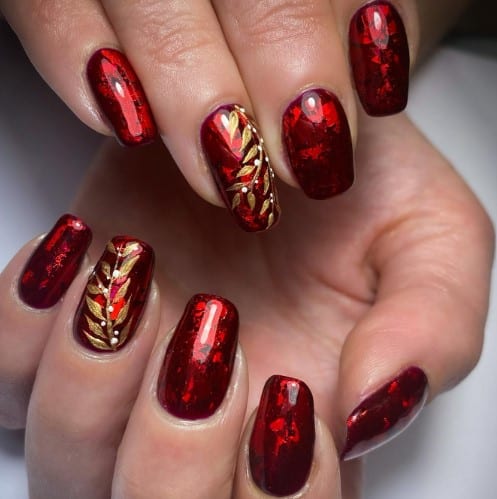 A woman's nails with red nails and gold foliage accent nail