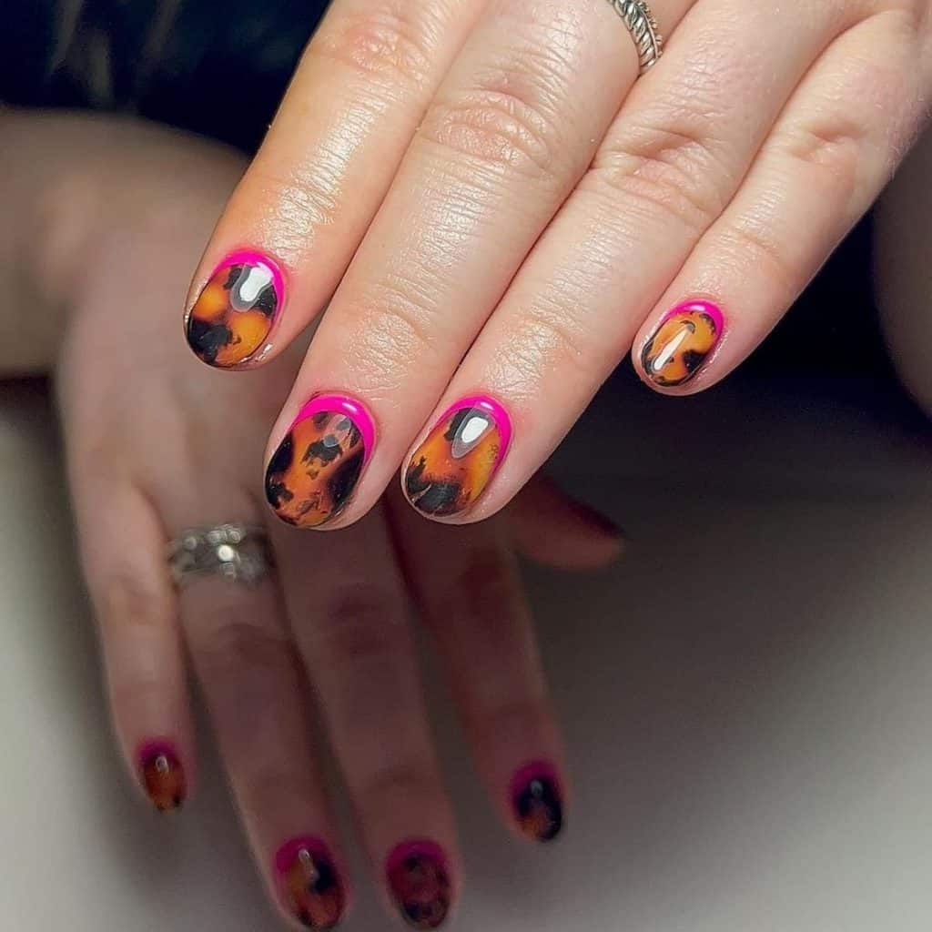 A woman's round tortoiseshell nails an electric touch with neon pink reverse French tips