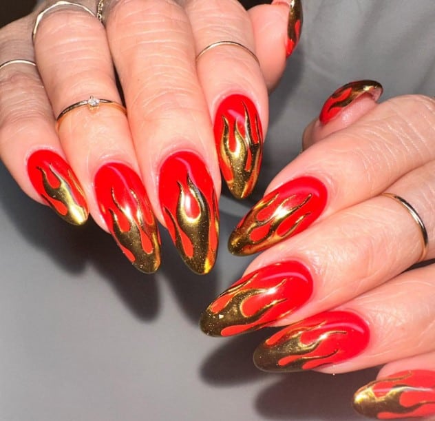 A woman with red and gold nails with flames on them.