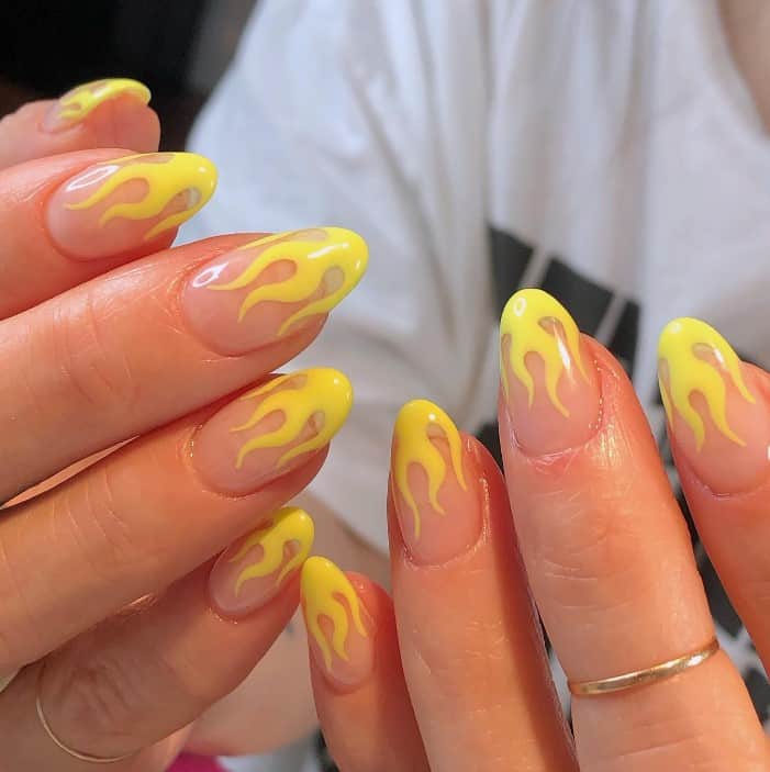 A woman's nails with nude base and with yellow flames on the tips
