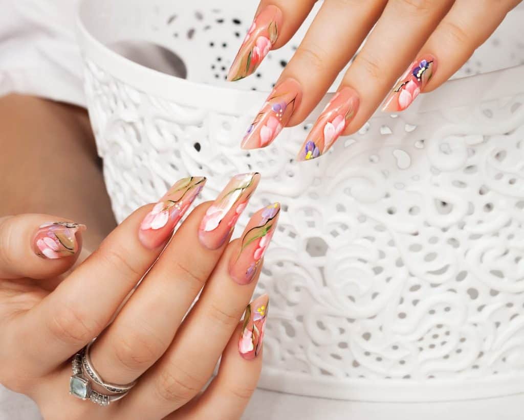 A woman is holding a white bowl and flaunting her nude base with floral nail art design