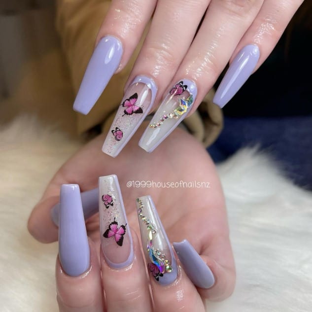 A woman's purple coffin nail design features soft lilac nails accentuated with clear ones featuring lilac reverse side French tip