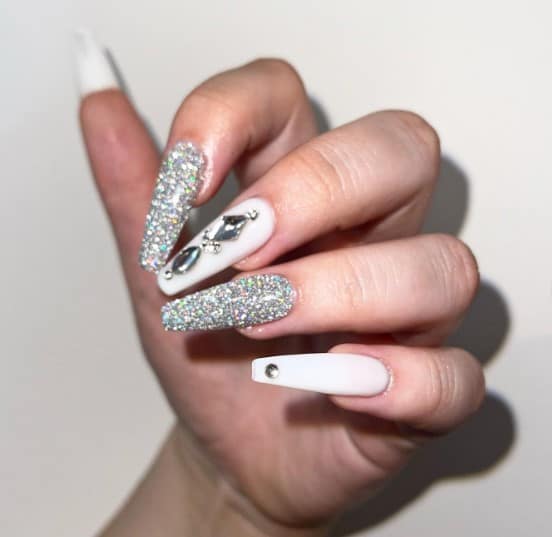 The mani features a stunning combination of classic white nails adorned with jewels and nails dipped in fine, sparkly silver glitter!