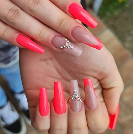 A woman's hands with vibrant pink and orange coffin nails.