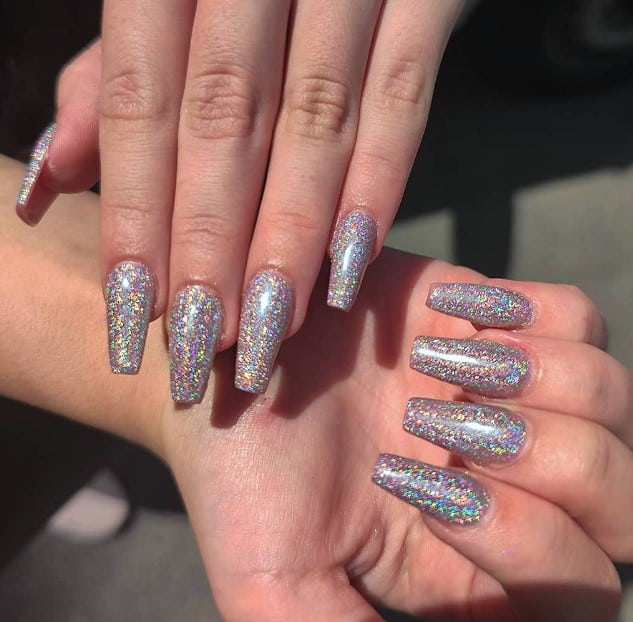 A woman's hands with dazzling coffin nails coated in glitter.