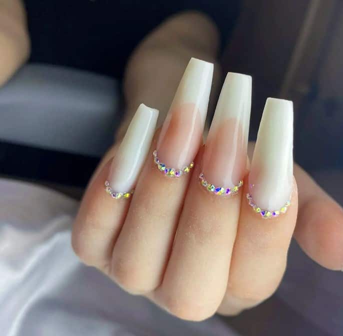 The long, plain white nails are beautifully paired with accent nails adorned with white French tips on a soft pink base, tastefully finished with chrome studs framing the cuticles. 
