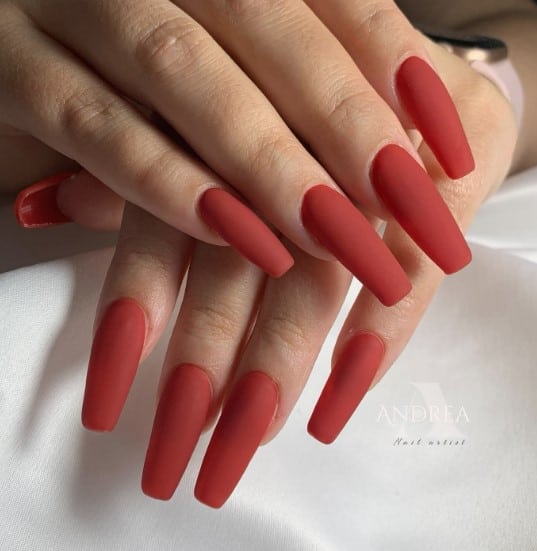 A woman's hands flaunting stylish coffin nails adorned with red nail polish.