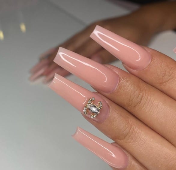 A woman's pink coffin nails with diamonds on them.
