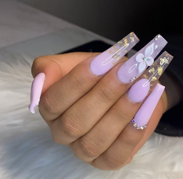 A woman's hand with stunning coffin nails in a mesmerizing purple and gold color scheme.