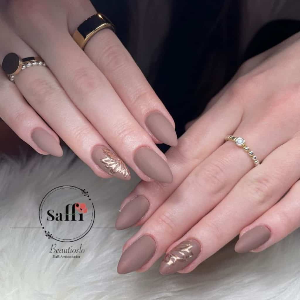 These matte taupe nails are accented by one that features delicate and intricate floral art in shimmering gold chrome