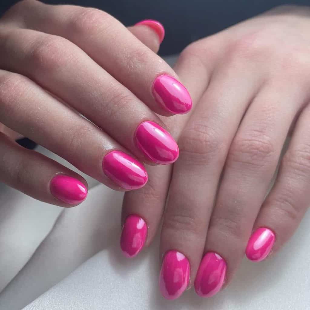 A woman's round nails in hot pink chrome