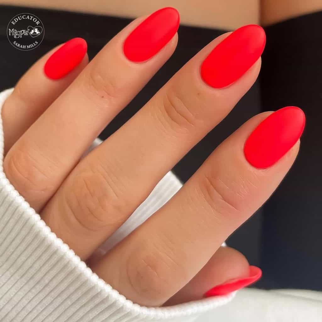 A woman's hand is holding a bright red nail polish.