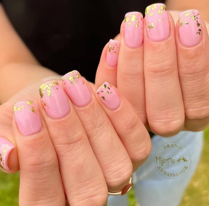 A woman with pink squoval nails with gold foil near the tips