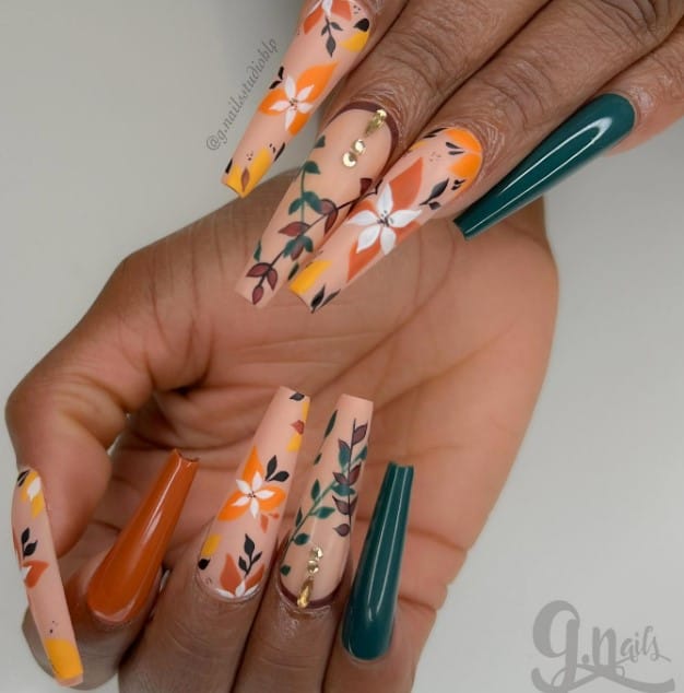 A woman's coffin nails are decorated with orange and green flowers.