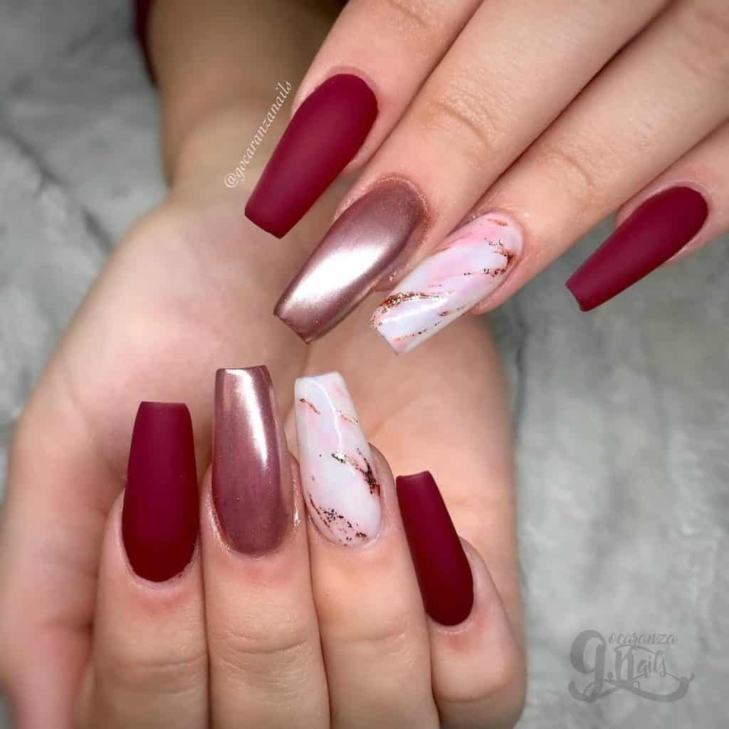 A woman's hands with burgundy and marble nails.