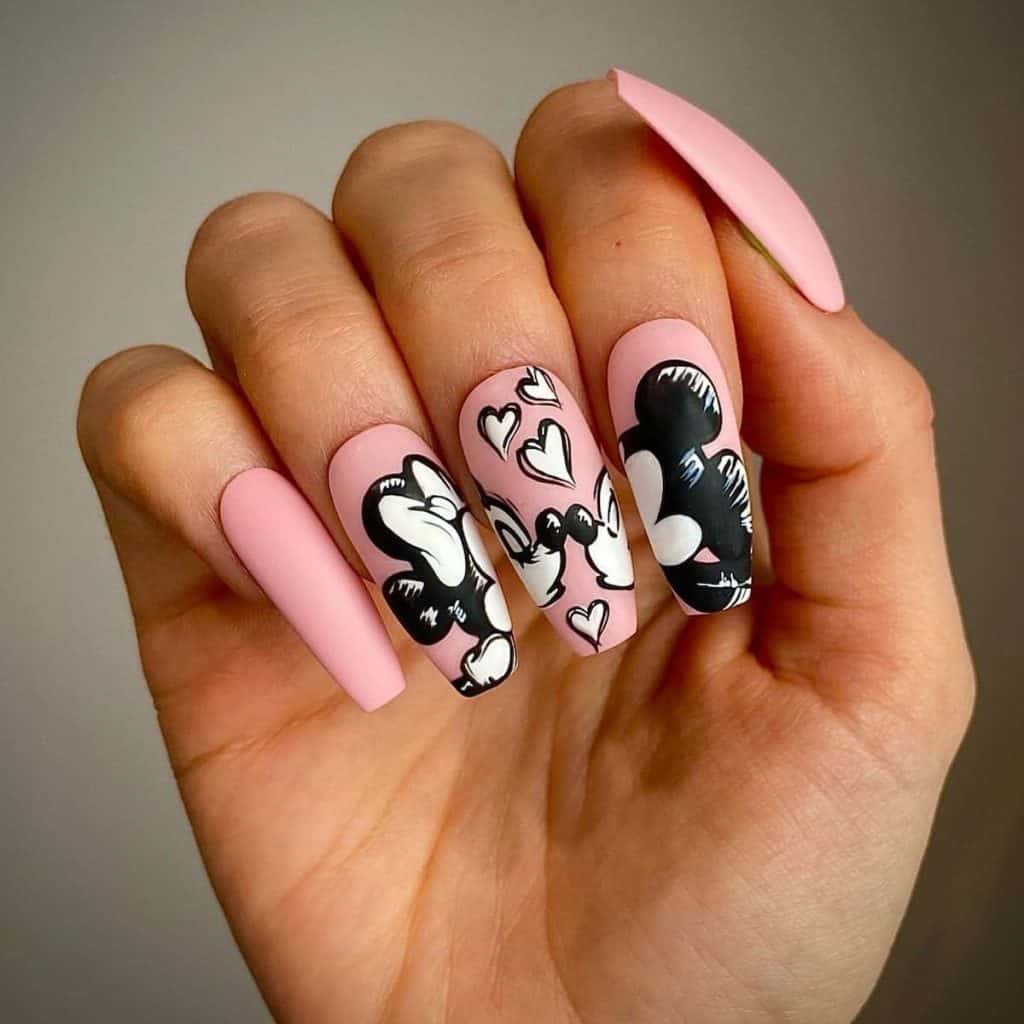 A woman's matte pink coffin nails that tell a tale of romance, featuring a black and white triptych of Minnie and Mickey Mouse, sealed with a kiss and flying hearts