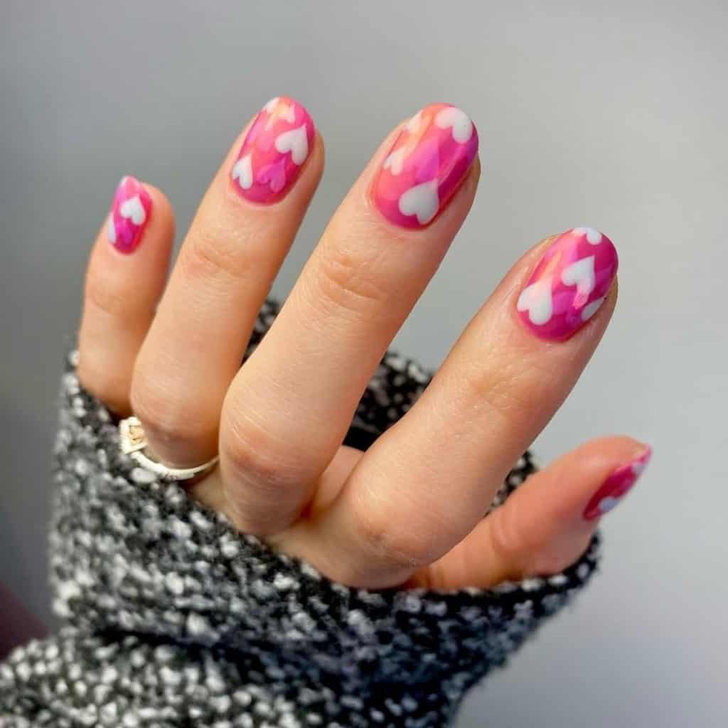 A woman's hot pink chrome nails topped with adorable hearts in white and a slightly lighter pink shade