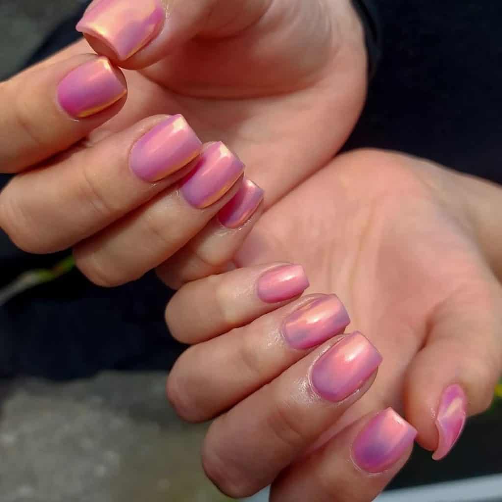 A woman's hands with squoval pink chrome nails