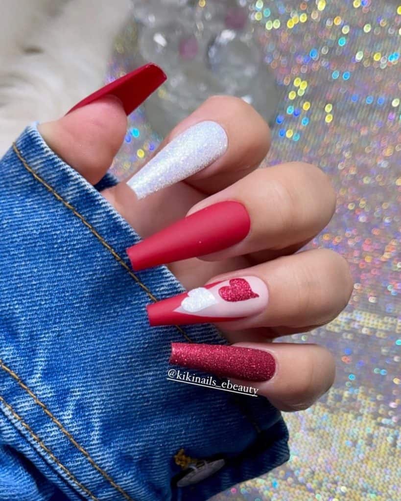 A woman's long coffin nails that exude elegance in plain matte red, along with white and red glitter. 