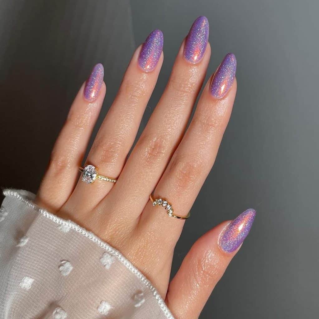 A woman's hand with nails coated in glittery violet jelly boasting an intense orange sparkle