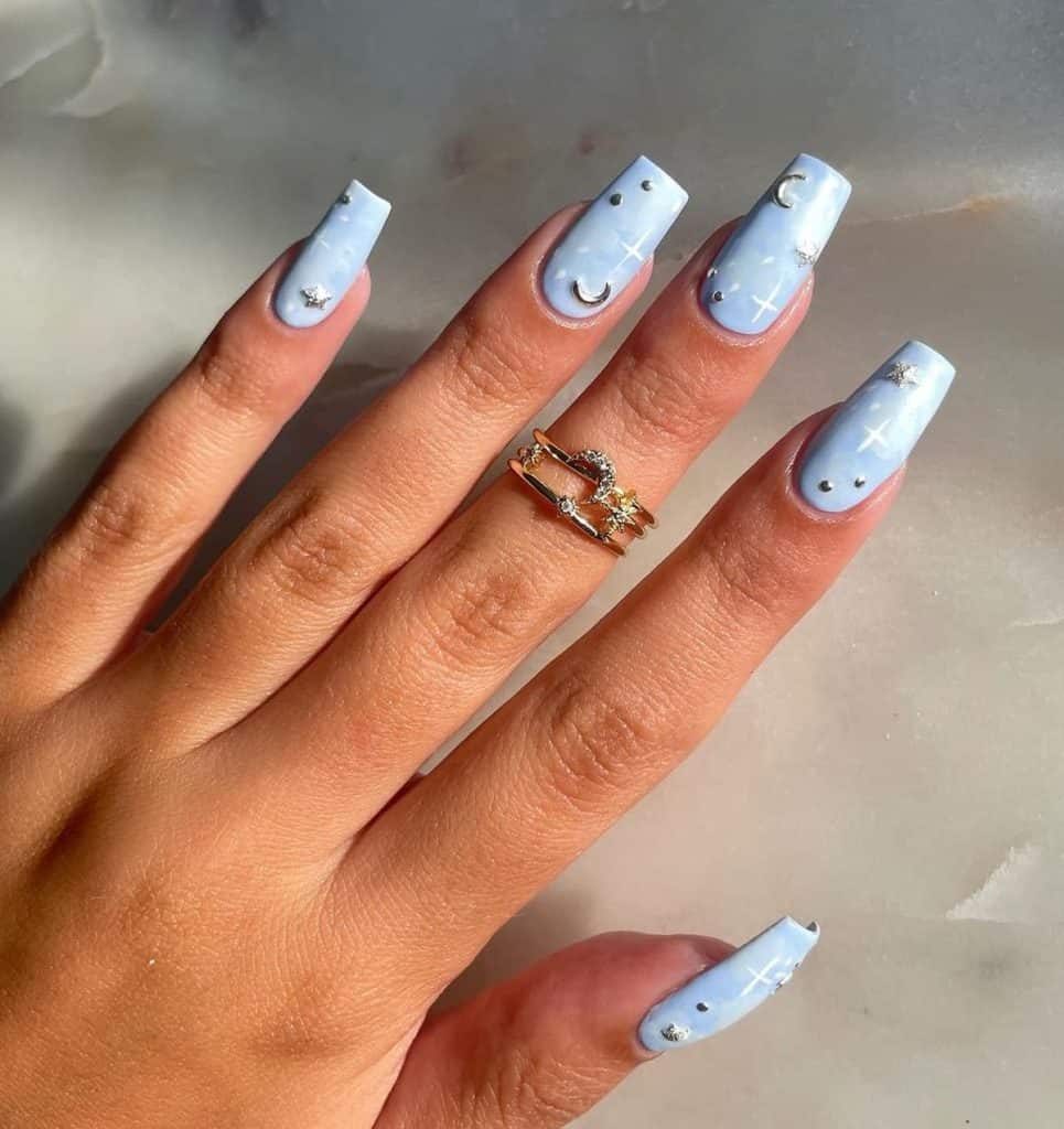 Matte sky blue nails become a night sky in this set decorated with white dots and crosses that mimic the stars, while silver studs add a celestial touch to complete the astral aesthetic.