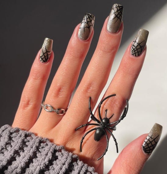 A woman's hand with a medium-length coffin nails showcase irregularly placed black spiderwebs in different corners
