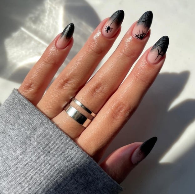 A woman's hand with black nails and a ring on it.