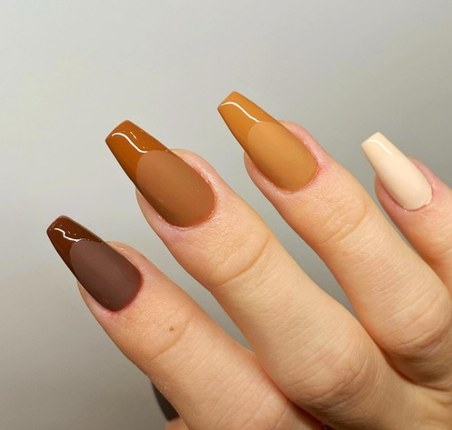 A woman's hand with brown coffin-shaped nails.