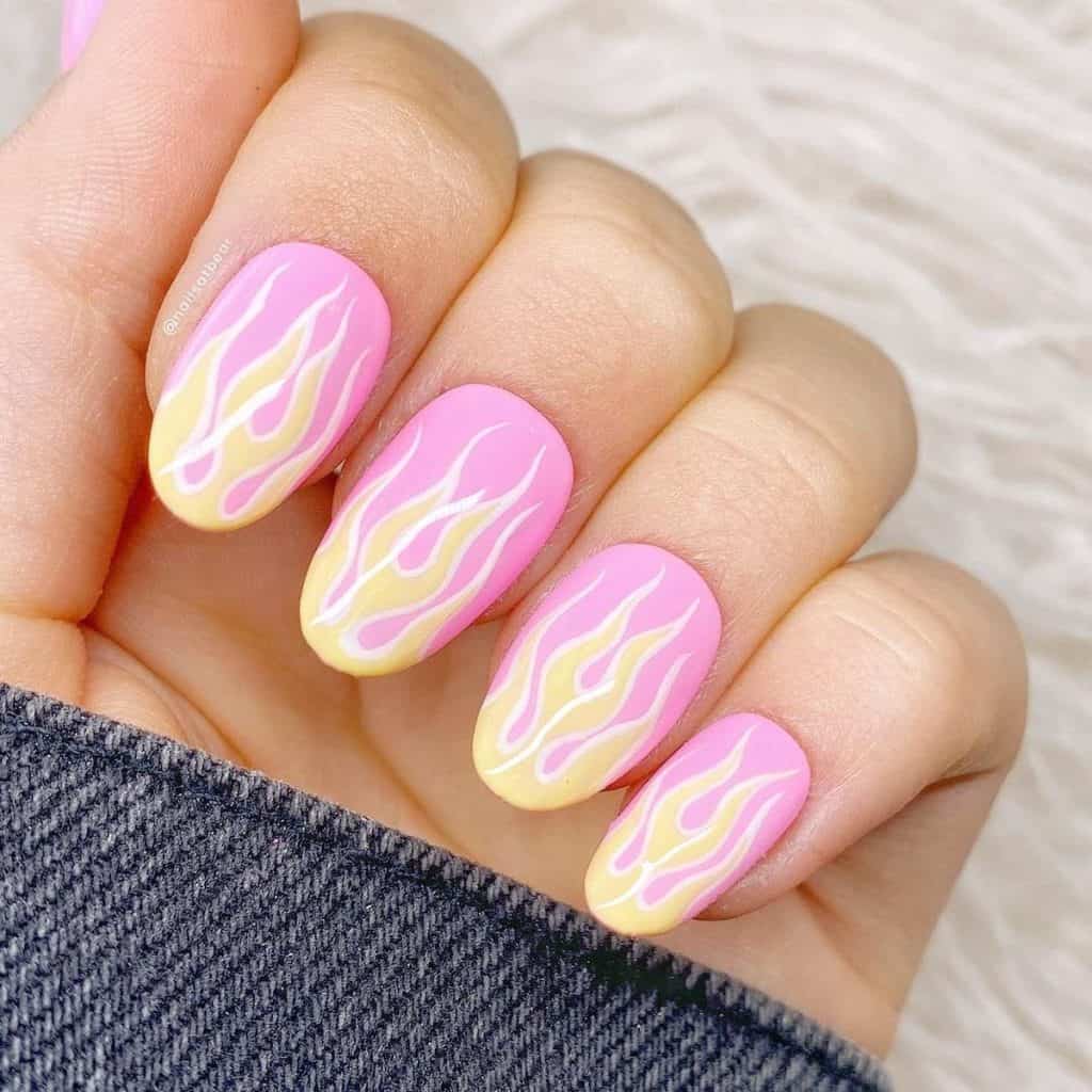 A woman's pink nails boasting yellow flame tips, each outlined in crisp white