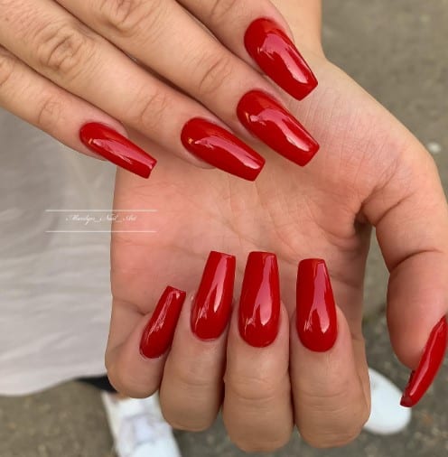 A woman's hand proudly displaying a pair of stylish red coffin nails.
