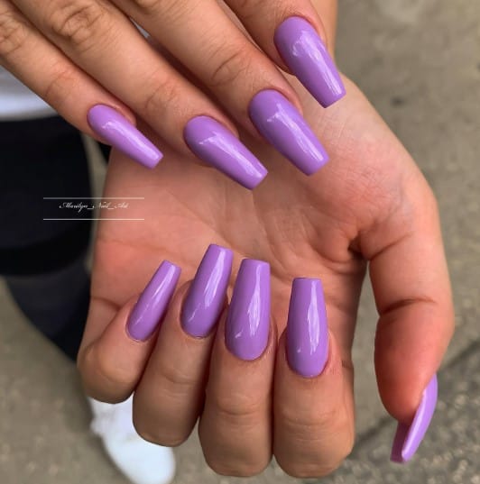 A woman's hand showcasing a mesmerizing pair of purple coffin nails.