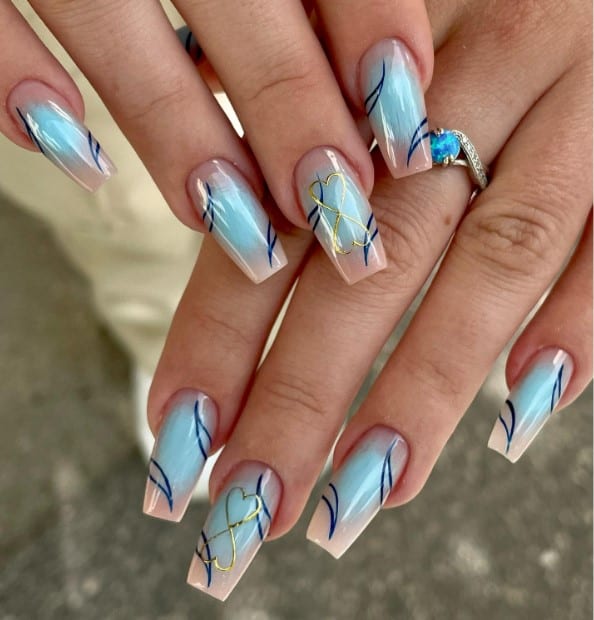 A woman's medium-length nail idea, featuring light pink coffin nails with a serene pale blue aura at the center and leaf-like patterns in dark blue