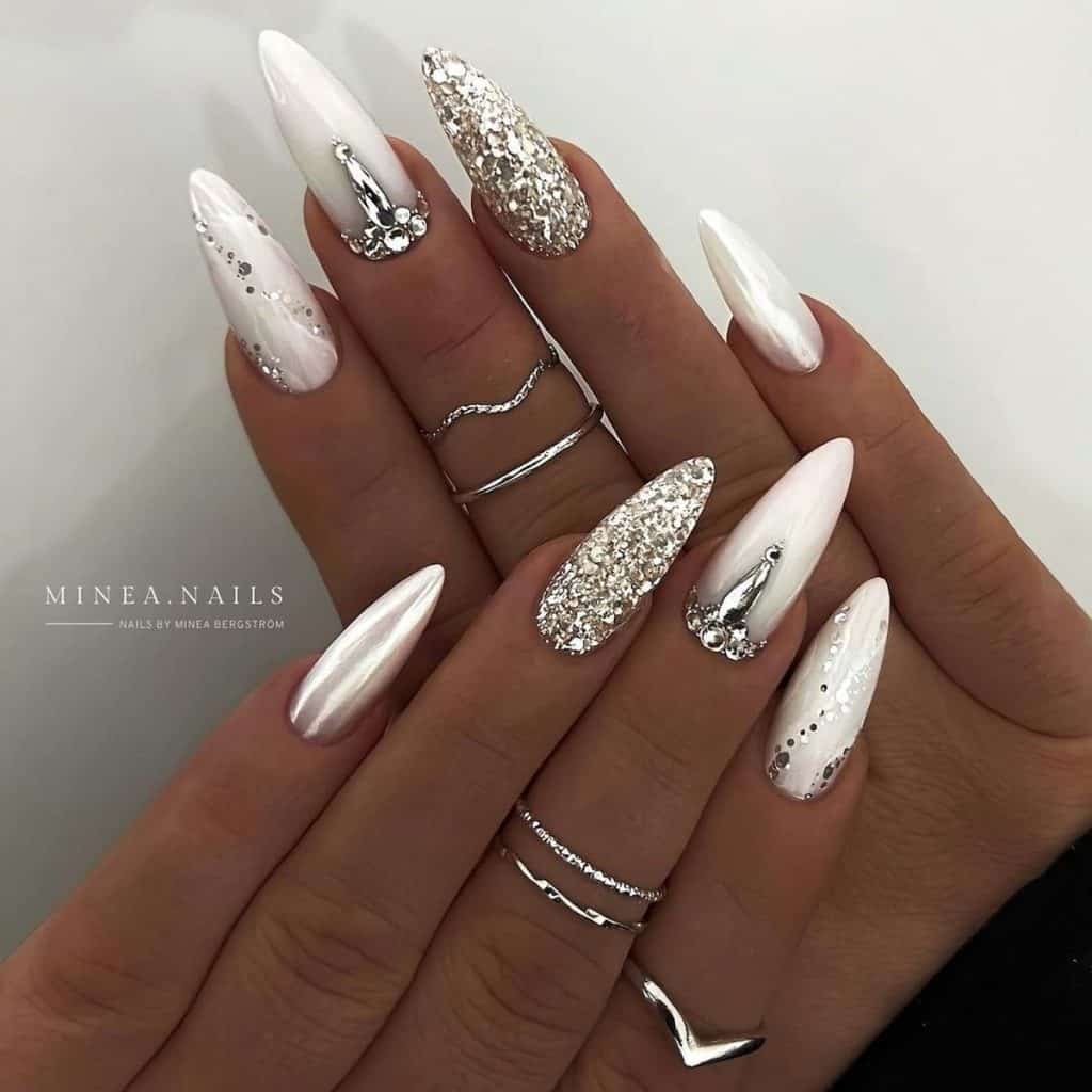 A woman's hand with shiny white nails, where chrome finishes meet the sparkle of silver glitter and the luxurious embrace of rhinestones