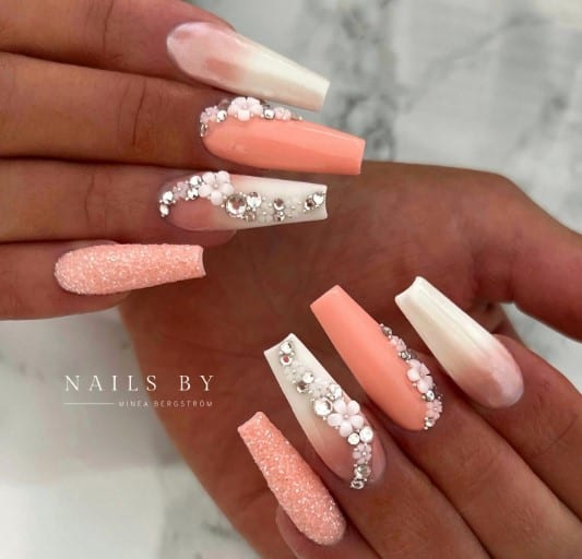 Coffin-shaped peach and white nails adorned with elegant diamonds.