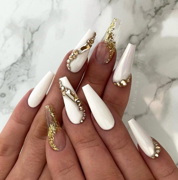 These nails feature spiraling studs and rhinestones to add a gorgeous sparkle to long, clean white polish, while the accent nail features a beautiful transparent acrylic nail with gold spirals.