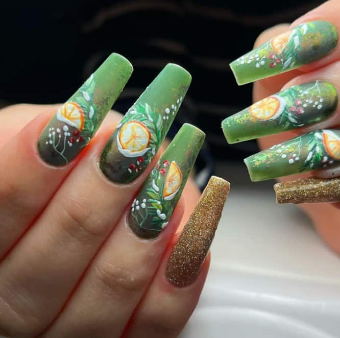 A woman's sheer green coffin nails adorned with delicate foliage and rich orange art